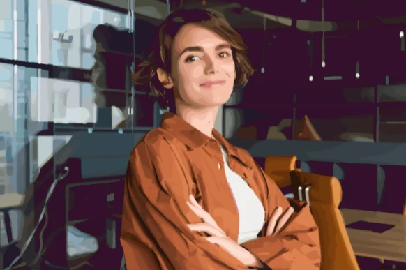 Mulher sorrindo, de braços cruzados, em um escritório